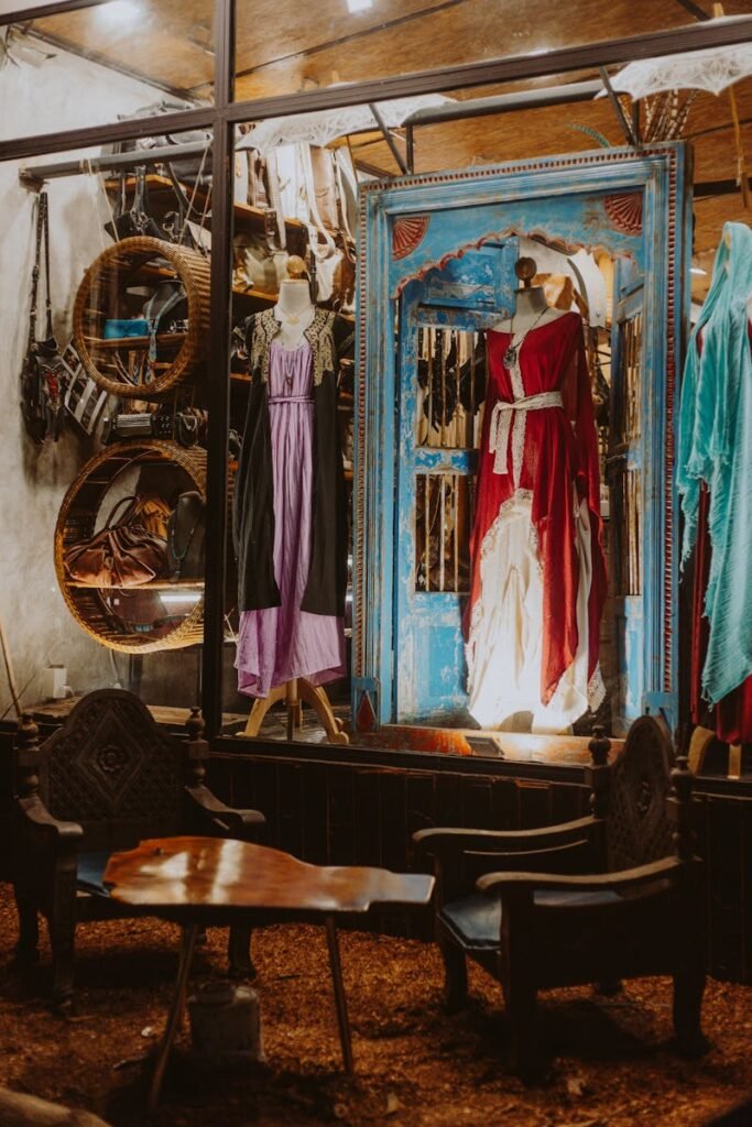 Mannequins in a rustic boutique showcase vintage dresses through glass panels.