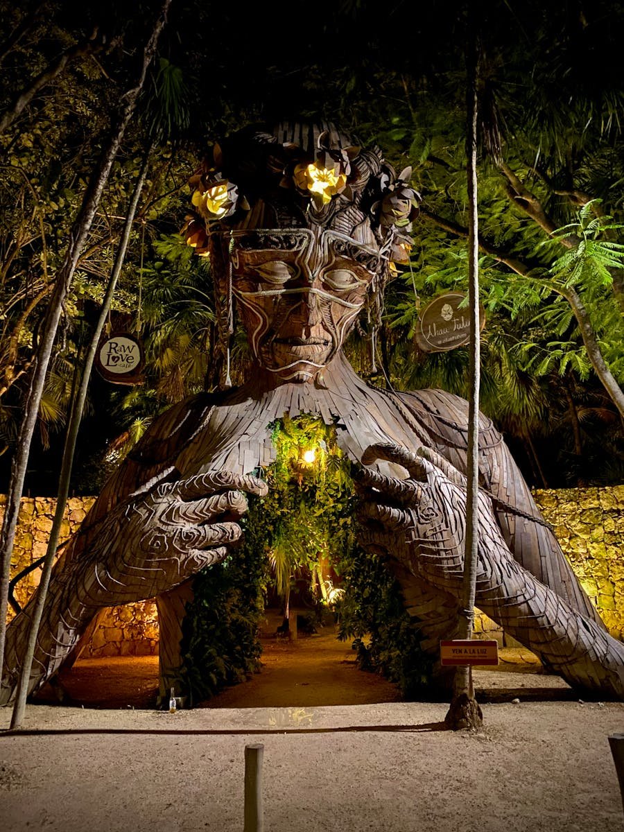 A stunning wooden sculpture entrance in Tulum, blending nature and art at night.